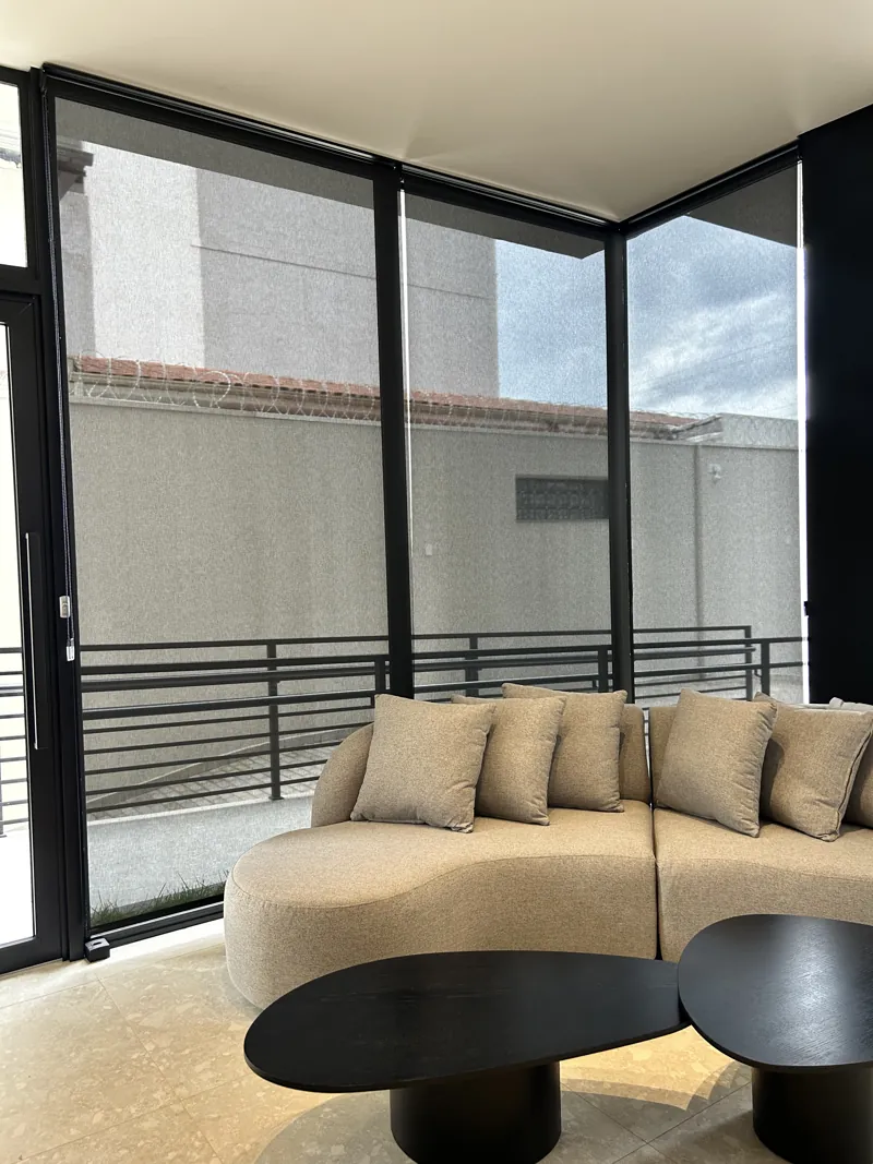 Rolô de tela solar em sala com paredes de vidro